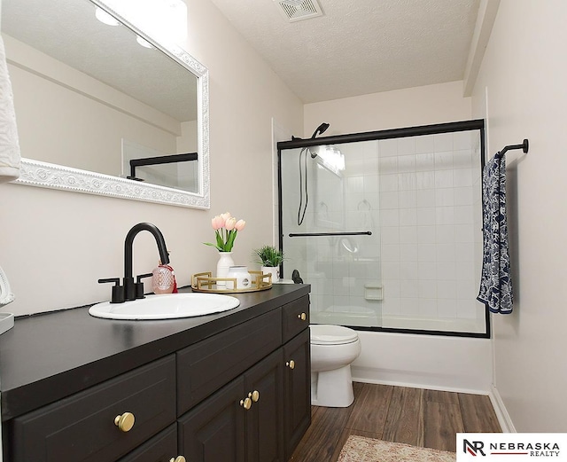 full bath featuring shower / bath combination with glass door, toilet, visible vents, wood finished floors, and vanity