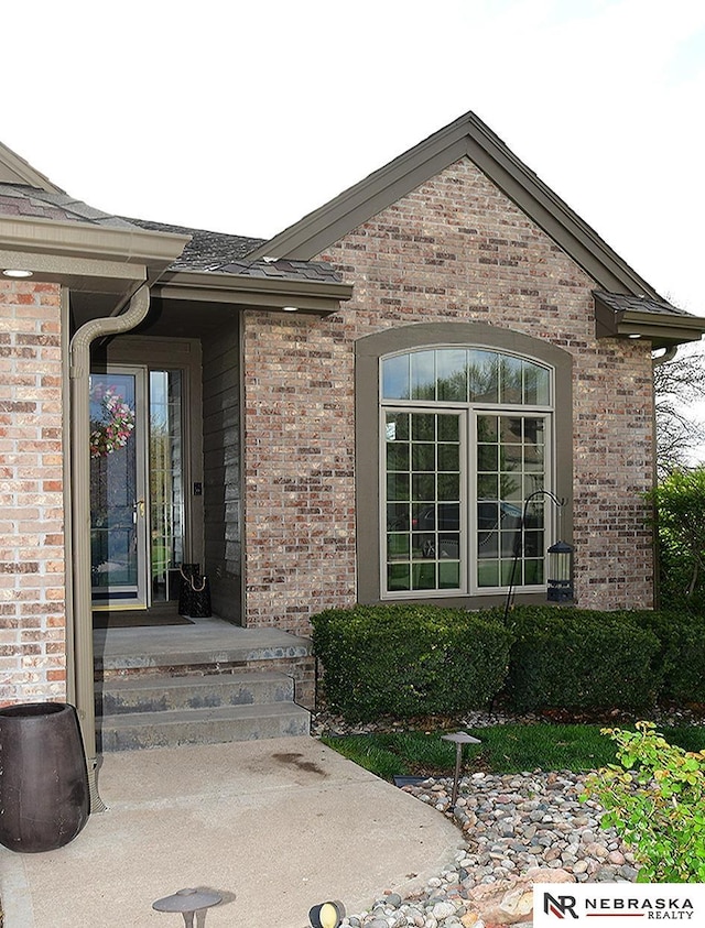 view of exterior entry featuring brick siding