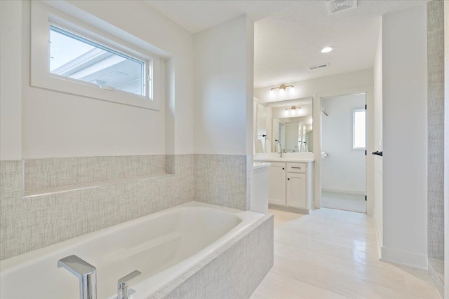 full bath featuring a garden tub, visible vents, a wealth of natural light, and vanity