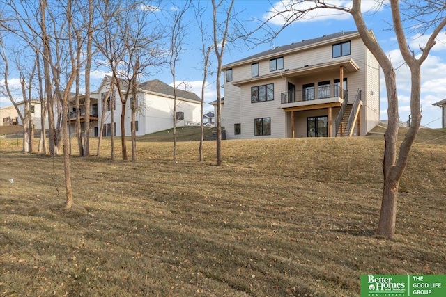 rear view of house with a lawn, stairs, and a balcony