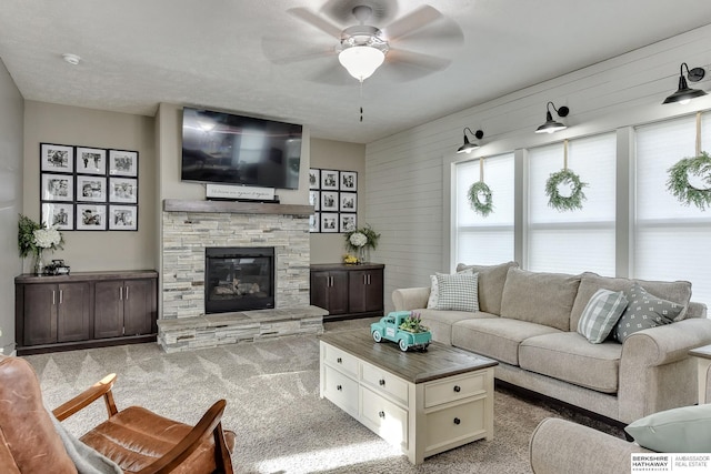 living room featuring carpet floors, ceiling fan, a fireplace, and wood walls