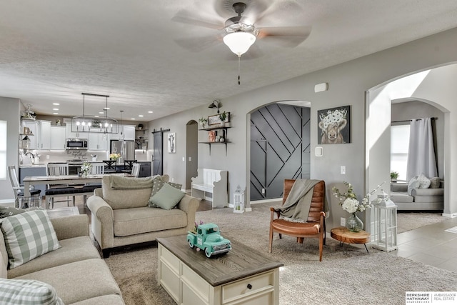 living room featuring baseboards, ceiling fan, recessed lighting, a textured ceiling, and arched walkways