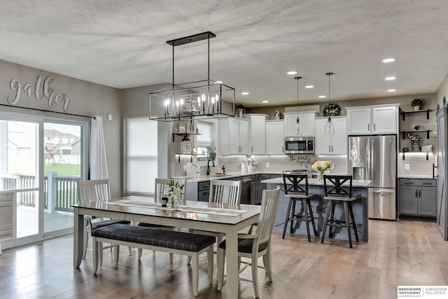 dining room featuring light wood-style floors, recessed lighting, and a textured ceiling