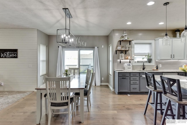 kitchen featuring gray cabinets, light stone countertops, a sink, recessed lighting, and light wood-style flooring
