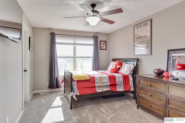 bedroom featuring baseboards, a ceiling fan, a textured ceiling, and light carpet
