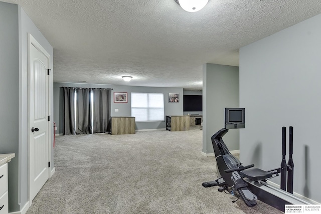 workout area with carpet floors, a textured ceiling, and baseboards