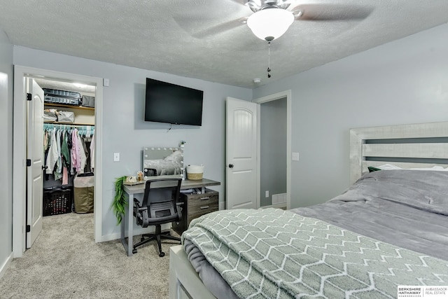 bedroom with a walk in closet, a textured ceiling, carpet, baseboards, and a closet