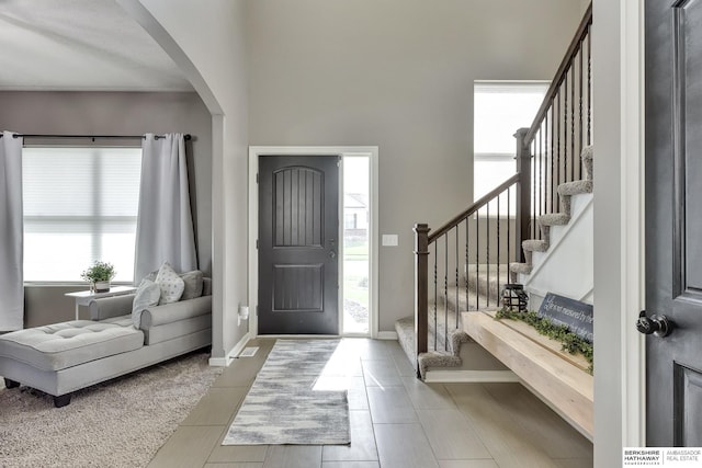 foyer entrance with a healthy amount of sunlight, arched walkways, and stairway