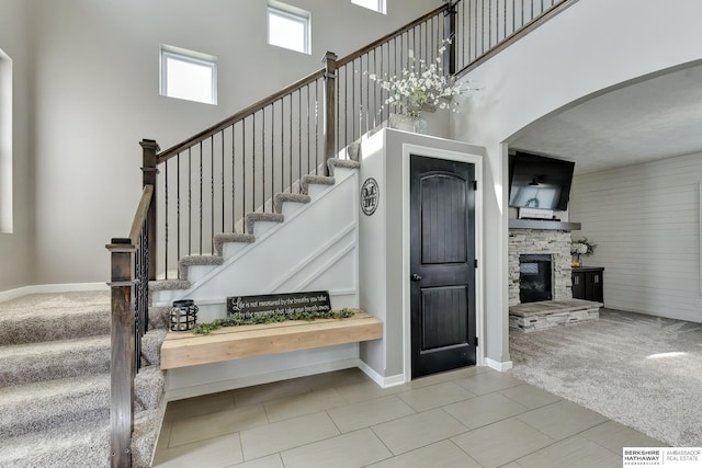 stairway with carpet flooring, a towering ceiling, and a fireplace