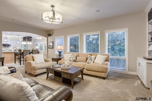living room with an inviting chandelier, baseboards, and light carpet