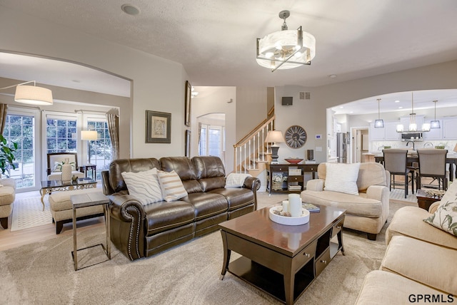 living area featuring arched walkways, an inviting chandelier, stairway, and visible vents