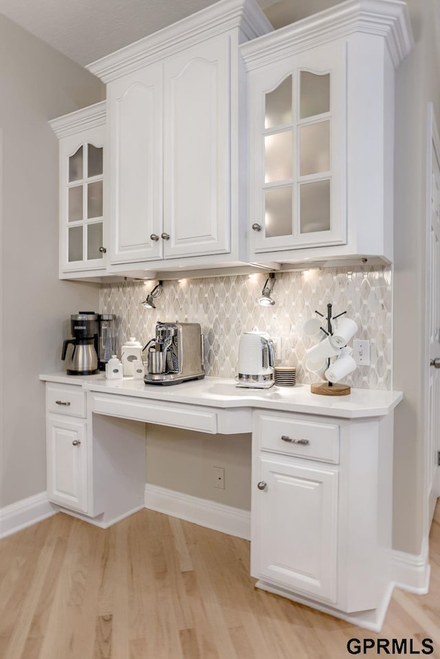 bar with light wood-style floors, baseboards, and backsplash