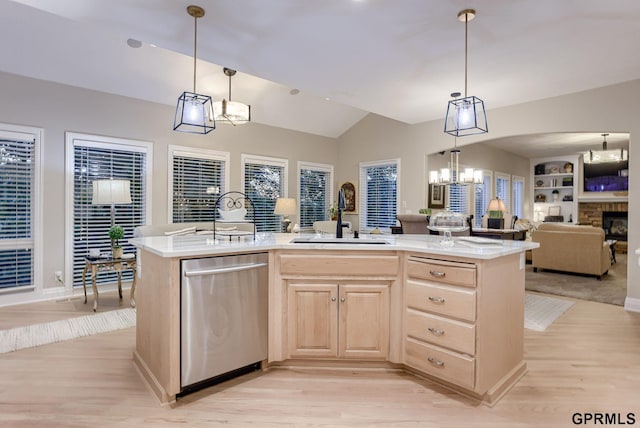 kitchen with stainless steel dishwasher, light brown cabinetry, open floor plan, a sink, and light wood finished floors