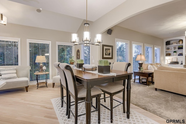 dining area with arched walkways, a chandelier, built in features, and light wood-style floors