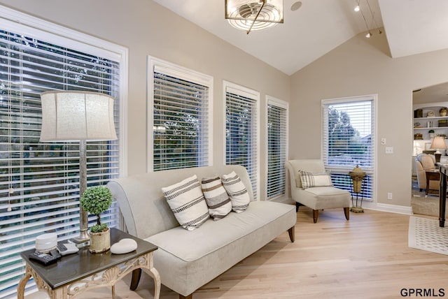 living area featuring baseboards, vaulted ceiling, and light wood-type flooring