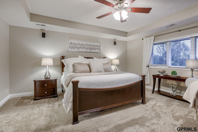 carpeted bedroom with visible vents, a raised ceiling, and baseboards