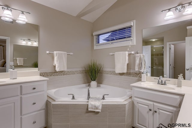 bathroom featuring lofted ceiling, a bath, two vanities, a sink, and a stall shower