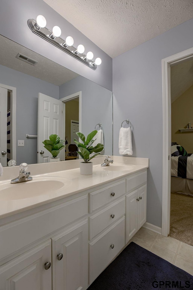 ensuite bathroom with visible vents, a sink, tile patterned floors, and double vanity