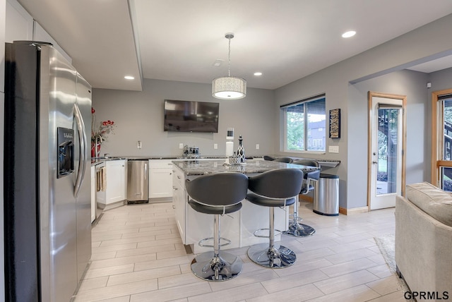 kitchen with white cabinets, light stone countertops, recessed lighting, a kitchen island, and stainless steel refrigerator with ice dispenser