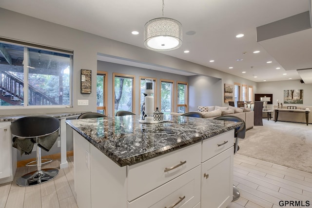 kitchen featuring recessed lighting, dark stone counters, a kitchen island, and white cabinets