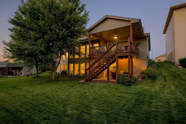 rear view of house featuring stairway, a lawn, and a wooden deck