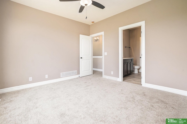 unfurnished bedroom featuring ensuite bath, light carpet, visible vents, and baseboards