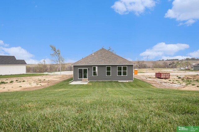 rear view of house with a lawn and roof with shingles