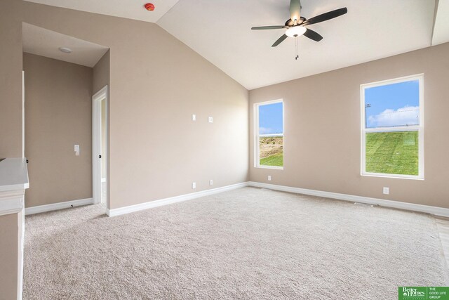spare room with vaulted ceiling, a ceiling fan, carpet floors, and baseboards