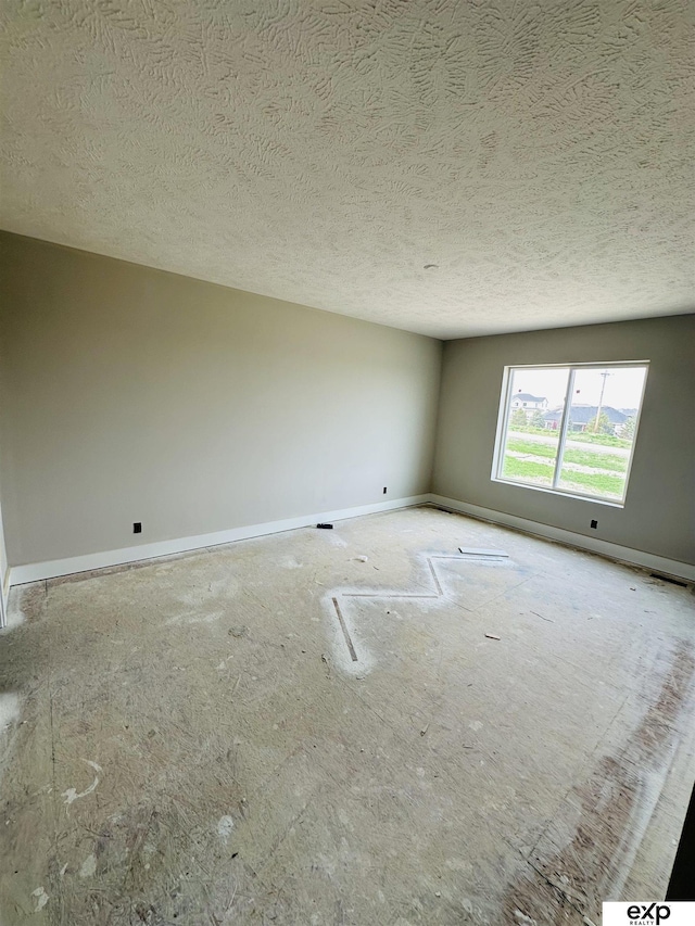 empty room with a textured ceiling and baseboards