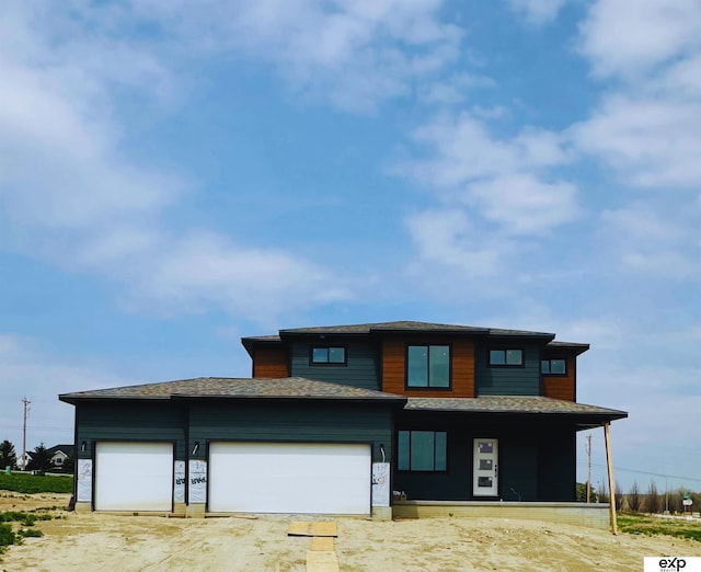 prairie-style house featuring a garage and roof with shingles