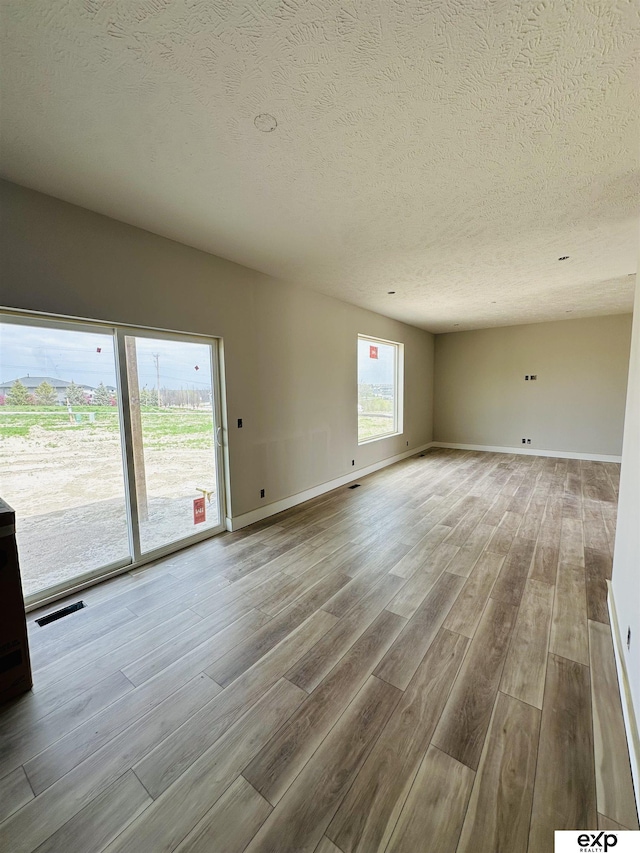 spare room with visible vents, baseboards, wood finished floors, and a textured ceiling