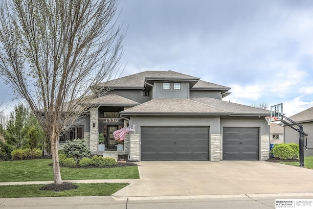 prairie-style house with stone siding, driveway, a front yard, and a garage