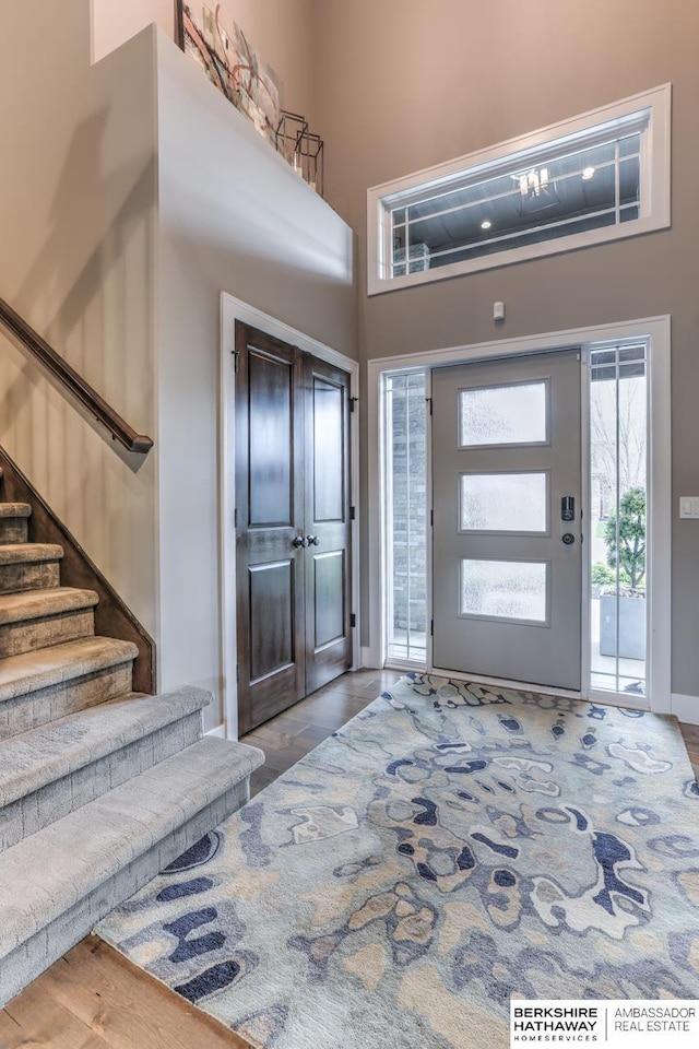 entrance foyer with stairway, a high ceiling, baseboards, and wood finished floors