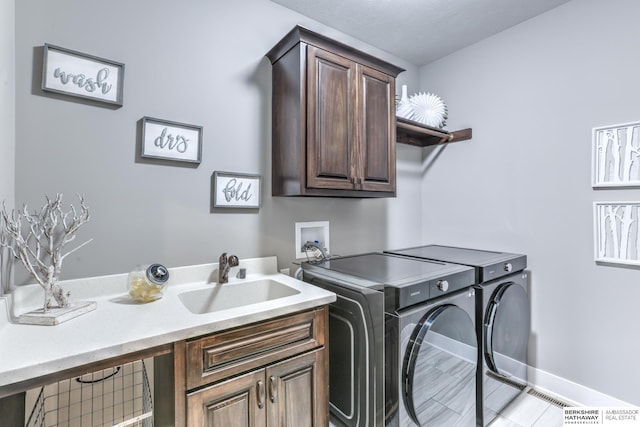 laundry area featuring washer and dryer, baseboards, cabinet space, and a sink