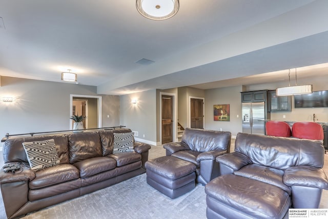 living room with stairway, baseboards, and light carpet