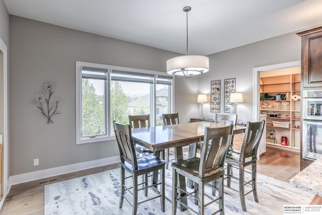 dining room featuring visible vents, baseboards, and wood finished floors