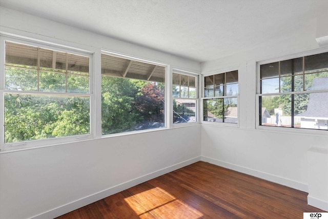 unfurnished sunroom with baseboards and wood finished floors