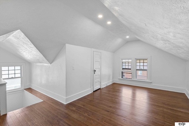 bonus room featuring a textured ceiling, lofted ceiling, wood finished floors, baseboards, and recessed lighting