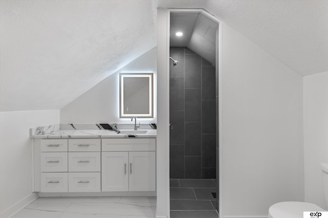full bath with a textured ceiling, lofted ceiling, toilet, tiled shower, and baseboards