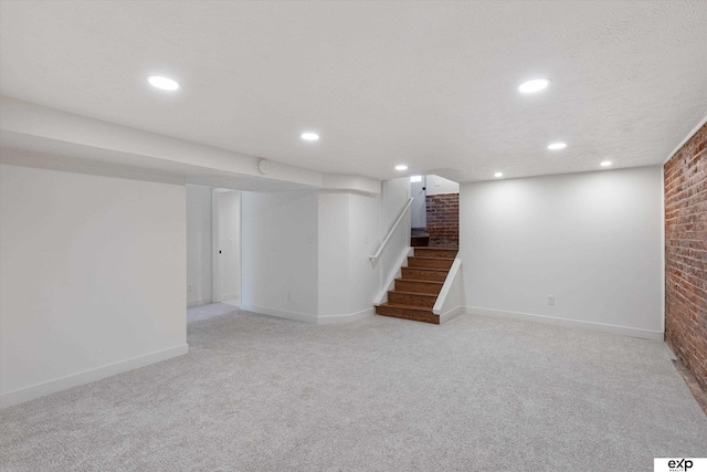 finished basement featuring brick wall, light colored carpet, stairs, baseboards, and recessed lighting