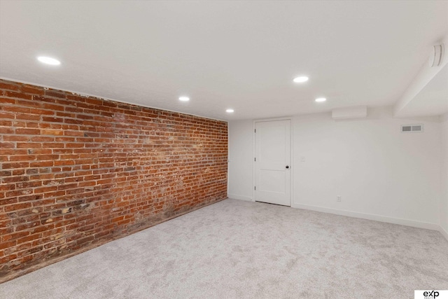 carpeted empty room with brick wall, recessed lighting, and baseboards