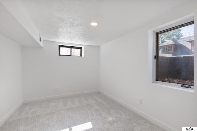 basement with a textured ceiling, carpet floors, baseboards, and recessed lighting