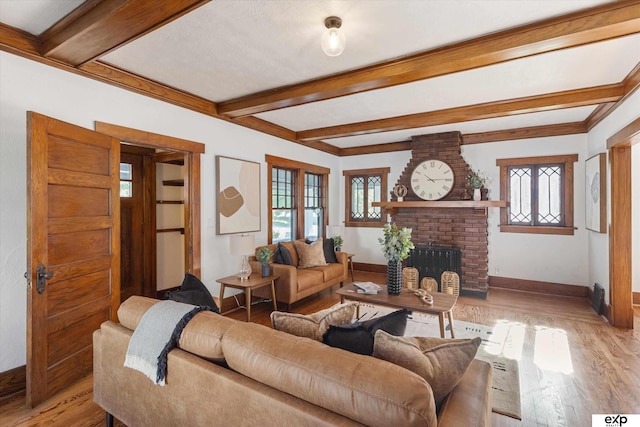 living room featuring baseboards, healthy amount of natural light, beamed ceiling, light wood finished floors, and a fireplace