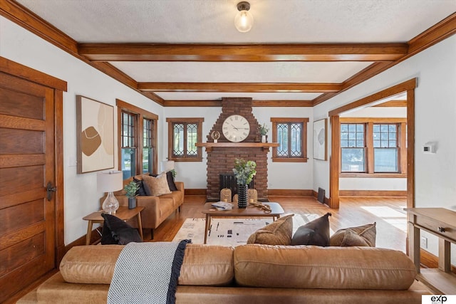 living area featuring baseboards, beamed ceiling, light wood finished floors, a brick fireplace, and a textured ceiling