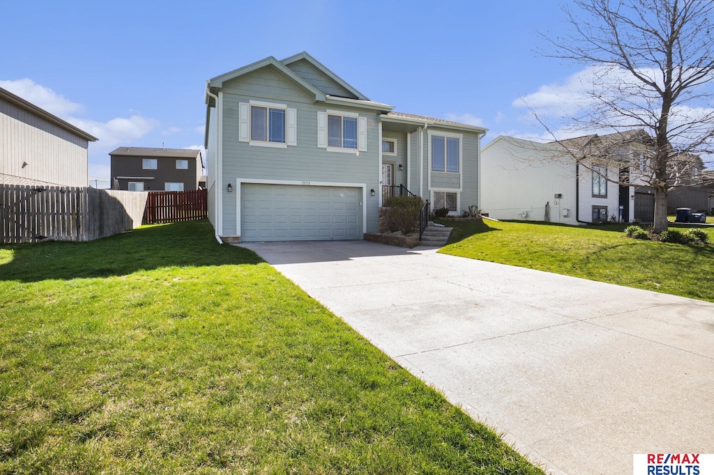 view of front facade featuring an attached garage, a front lawn, fence, and concrete driveway