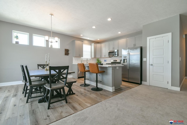 kitchen featuring appliances with stainless steel finishes, a breakfast bar, an inviting chandelier, recessed lighting, and a kitchen island