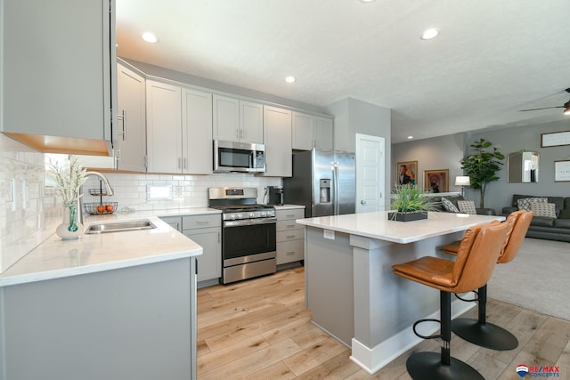 kitchen with appliances with stainless steel finishes, a sink, light wood-style floors, a breakfast bar area, and open floor plan