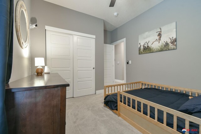 bedroom featuring light colored carpet, ceiling fan, and a closet