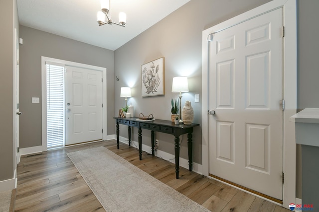 entrance foyer featuring light wood-type flooring, baseboards, and a chandelier