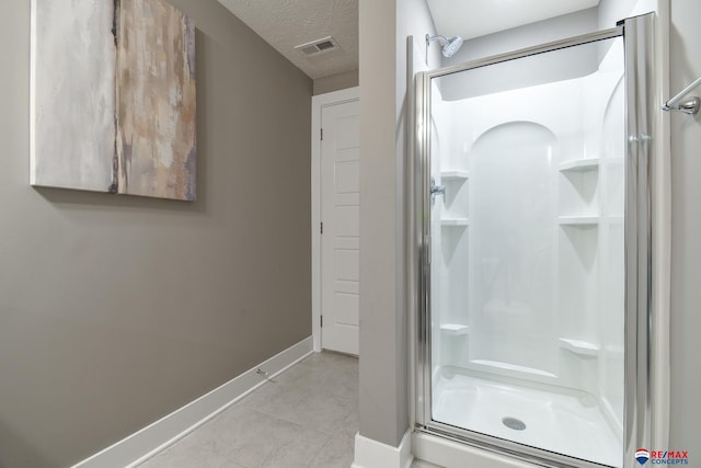 bathroom with a textured ceiling, visible vents, a stall shower, baseboards, and tile patterned floors